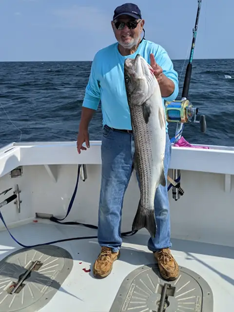 A man shows off his fish on the deck of Tuna Tail Charters' sport fishing charter.